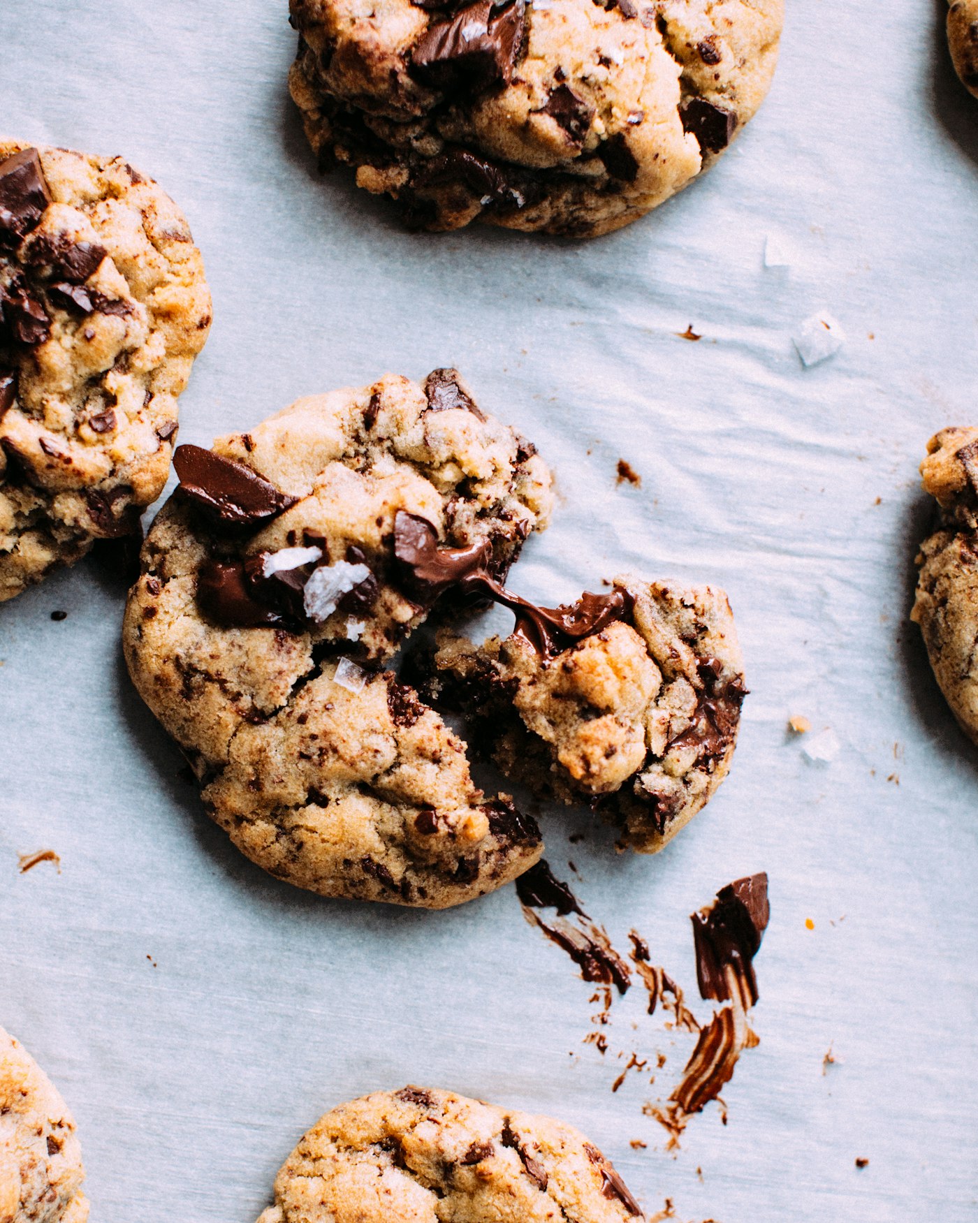 Fresh-baked chocolate chunk cookies with flaky sea salt on parchment